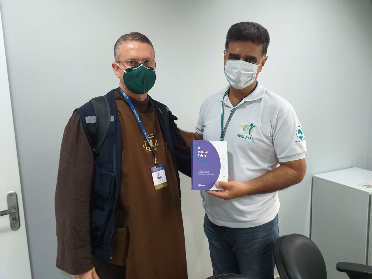 El miembro de la Mesa Directiva de Esfera Fray Luciano entrega un Manual en portugués a Eli Mansur de AVSI Brasil en el estado de Roraima, Brasil.